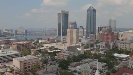 An-aerial-pull-back-shot-with-the-Jacksonville-downtown-skyline-and-city-surrounded-by-water-on-a-mildly-overcast-day