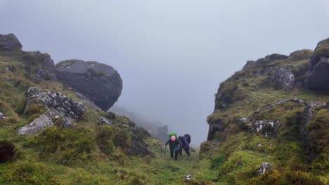Hillwalkers-climbing-up-a-gulley-in-The-Comeragh-Mountains-Waterford-on-a-dull-overcast-winter-day