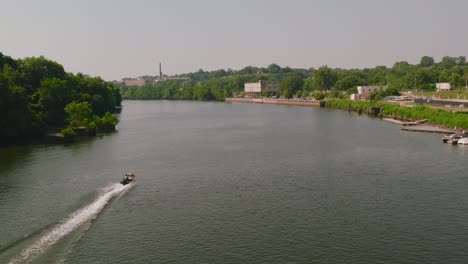 Eine-Luftaufnahme-über-Dem-Fluss-In-Richmond,-Die-Einem-Boot-Am-Wasser-Entlang-Folgt-Und-In-Die-Skyline-Der-Stadt-übergeht