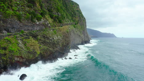 Coastline-way-with-cliff-waves-mountains-in-clouds-Panoramic-Ocean-Horizon-panoramic-sky-lifting-drone-shot-madeira