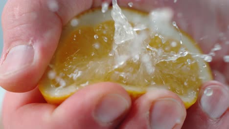 Person-Squeezing-Lemon-Half-with-Juice-Droplets-in-Air