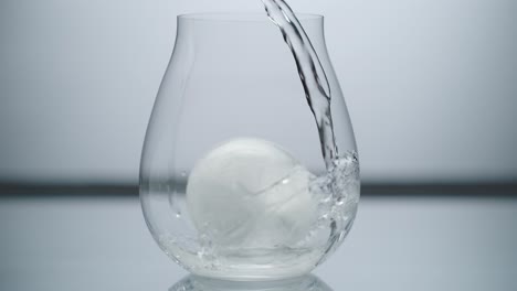 Water-Cascading-Over-Round-Ice-Cube-in-Glass