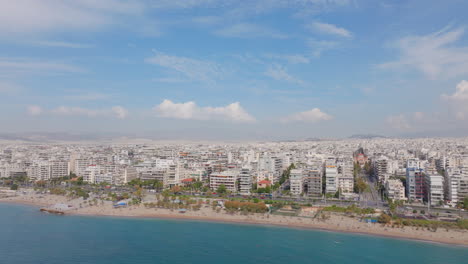 Aufsteigende-Luftaufnahme-Vom-Blauen-Meer-Zu-Den-Weißen-Gebäuden-Der-Stadt-Athen-In-Griechenland