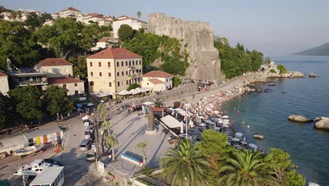 Umlaufende-Aufnahme-Des-Kleinen-Strandes-Von-Herceg-Novi-An-Der-Promenade-Mit-Der-Festung-Forte-Mare-Im-Hintergrund,-Montenegro