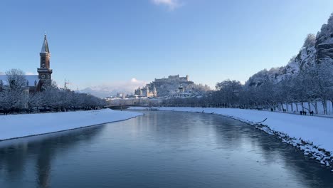 Establishing-shot-of-river-Salzach-in-snowy-white-Salzburg-city,-Austria