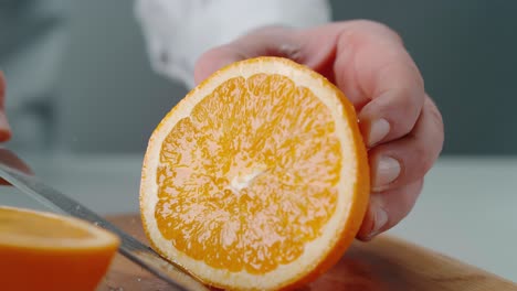 Person-Cutting-Orange-on-Wooden-Cutting-Board