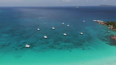 Drohnenaufnahme-Einiger-Boote-Unter-Anker-An-Einem-Wunderschönen-Tropischen-Strand-In-Kristallklarem-Wasser-Auf-Den-Seychellen
