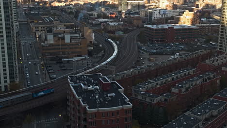 Trains-moving-on-the-main-railroad-tracks,-sunny-evening-in-Chicago---Aerial-view
