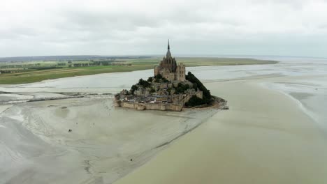 mont-saint-michel-going-towards-don-camaro-side,-the-castle-has-lots-of-trees-and-low-rise-houses