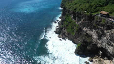 Waves-crashing-into-the-shores-of-Uluwatu,-Bali,-Indonesia-on-a-hot-summers-afternoon