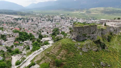 Drohnenansicht-In-Albanien,-Die-In-Der-Stadt-Gjirokaster-über-Eine-Mittelalterliche-Burg-Auf-Einer-Hochgelegenen-Festung-Fliegt-Und-Die-Ziegelbraunen-Dachhäuser-Zeigt