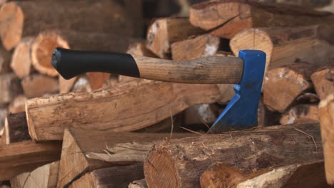 Person-sticking-work-axe-into-a-cut-and-stacked-piece-of-log