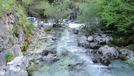 Drone-view-in-Albania-in-the-alps-flying-on-top-of-a-rapids-river-surrounded-by-green-and-rocky-mountain-in-Theth