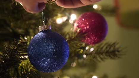 Close-Up-of-a-Person-Decorating-a-Christmas-Tree-with-Sparkly-Ornaments