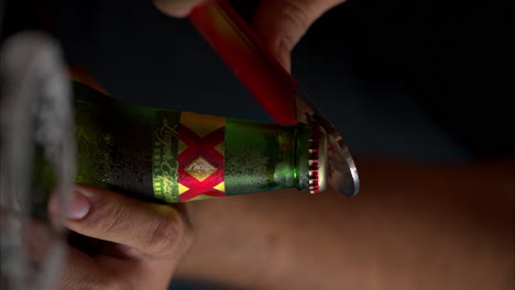 Vertical-slow-motion-close-up-of-a-man-opening-a-bottle-of-XX-Lager-beer-in-a-restaurant-in-Mexico