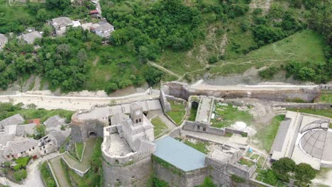 Drohnenansicht-In-Albanien,-Die-In-Der-Stadt-Gjirokaster-über-Eine-Mittelalterliche-Burg-Auf-Einer-Hochgelegenen-Festung-Fliegt-Und-Die-Ziegelbraunen-Dachhäuser-Zeigt