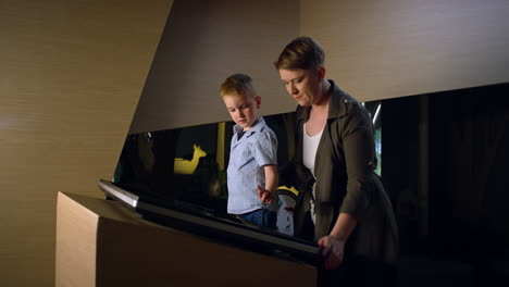 Boy-and-his-mother-using-a-touch-screen-display-in-a-museum,-handheld-shot