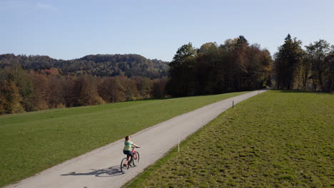Radfahrerin-Auf-Einer-Landstraße,-Die-Die-Herbstlandschaft-Genießt,-Luftaufnahme
