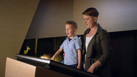 Junge-Mit-Seiner-Mutter-In-Einem-Museum,-Schaut-Auf-Ein-Touchscreen-Display,-Handaufnahme