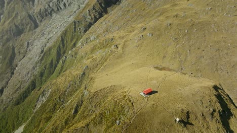 Mountain-cabin-on-grass-plateau-in-New-Zealand-alpine-landscape,-Brewster-Hut