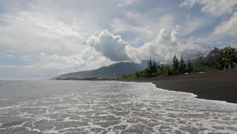 Taharuu-Strand-Auf-Tahiti-In-Französisch-Polynesien-Mit-Schwarzem-Sand-Und-Wellen-Vom-Pazifischen-Ozean-Und-Surfern-Im-Hintergrund