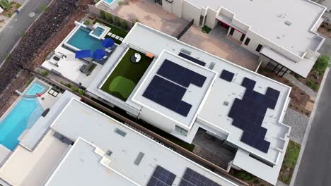 Drone-Shot-of-Solar-Panels-Installed-on-Rooftop-of-Luxury-Mansions-With-Swimming-Pools-in-Henderson,-Nevada-USA