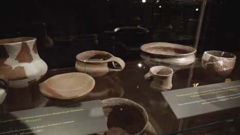 ancient-clay-pots-and-dishes-in-glass-case-at-the-exhibition-in-the-museum-of-Biskupin,-Poland