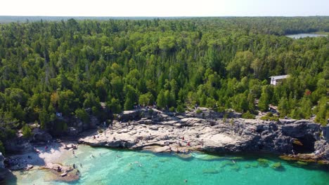 Aerial-Georgian-Bay,-Canada-blue-water,-people-swimming,-white-pine-forest