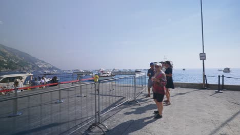 Amalfi-Positano-Italy-Immersive-Travel-Tourism-Mediterranean-Sea-Coast-Water-Europe,-Walking,-4K-|-Tourists-Watching-Boats-Depart-From-Pier