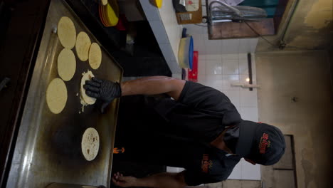 Vertical-slow-motion-of-a-man-cooking-some-tortillas-and-making-a-quesadilla-on-the-griddle-wearing-black-latex-gloves