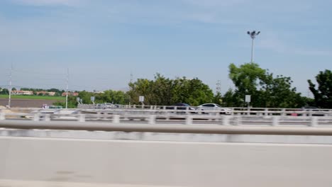 Speeding-down-the-bridge-while-on-the-other-lane-cars-and-other-vehicles-are-also-revealed-also-an-urban-community,-Kanchanaphisek-Road,-Thailand