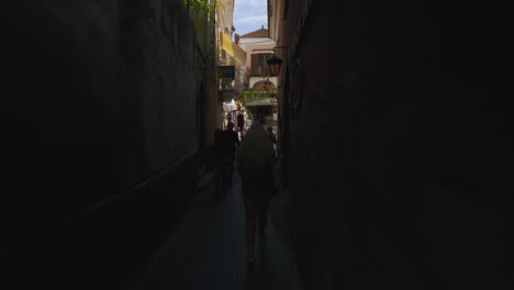 Amalfi-Positano-Italy-Immersive-Travel-Tourism-Mediterranean-Sea-Coast-Water-Europe,-Walking,-4K-|-Couple,-Dark-Crowded-Alley,-Congested,-Below-Famous-Mountainside-Cliffs,-Shaky,-Anxiety-Inducing