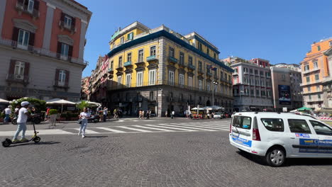 City-square-bustling-with-activity,-vehicles-and-pedestrians,-sunny-ambiance---Naples