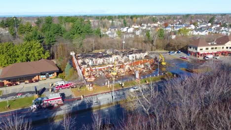 Drone-shot-of-a-garage-building-that-was-badly-burned-being-cleaned-by-the-local-fire-department-using-heavy-equipment