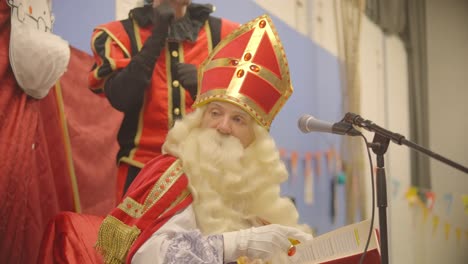 Saint-Nicholas-at-celebration-on-stage-with-a-microphone-and-his-assistent-Pete