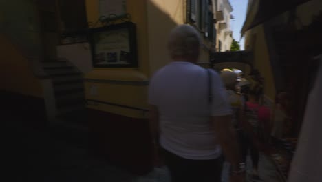 Amalfi-Positano-Italy-Immersive-Travel-Tourism-Mediterranean-Sea-Coast-Water-Europe,-Walking,-4K-|-Moving-Through-Busy-Tourist-Crowds-in-Dark-Alley-Near-Clothing-Retailer