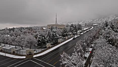 Drone-flies-above-snowy-trees-and-road-to-establish-Provo-LDS-Mormon-Temple
