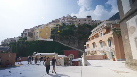 Amalfi-Positano-Italy-Immersive-Travel-Tourism-Mediterranean-Sea-Coast-Water-Europe,-Walking,-4K-|-Fast-Turn-Towards-Scenic-Mountainside-Homes-as-Tourists-Walk,-Rest,-and-Birds-Fly,-Shaky