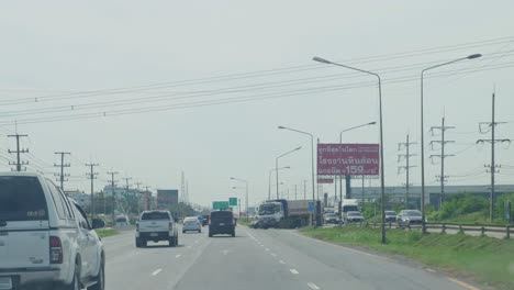 A-U-turn-is-revealed-on-the-right-with-a-truck-and-other-vehicles-ready-to-turn-as-seen-down-Mittraphap-Road,-Thailand