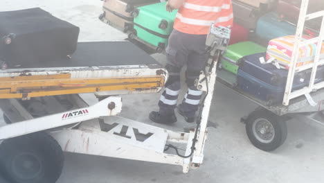 Airport-ground-crew-handling-luggage-on-conveyor,-busy-tarmac-area