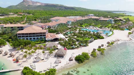 High-angle-aerial-orbit-around-white-sand-beautiful-Caribbean-resort-and-crystal-clear-water,-Santa-Barbara-beach-Curacao