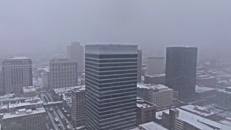 Aerial-view-of-downtown-Salt-Lake-City-skyline-as-snow-falls-from-gloomy-sky