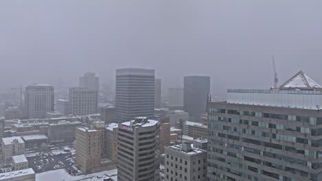 Gray-snowy-sky-over-Salt-Lake-City-skyline-in-winter,-aerial-dolly
