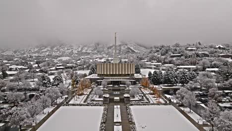 Symmetrical-aerial-dolly-push-in-to-Provo-LDS-Mormon-Temple-in-snow,-Wasatch-mountain-range-behind