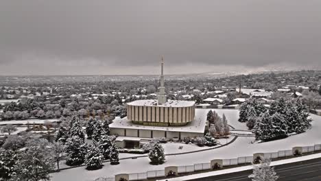 Aerial-orbit-of-southern-side-of-Provo-LDS-Mormon-Temple-covered-in-snow-on-grey-overcast-day