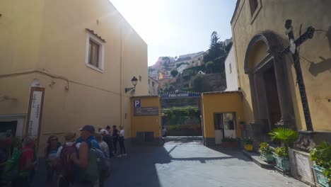 Amalfi-Positano-Italy-Immersive-Travel-Tourism-Mediterranean-Sea-Coast-Water-Europe,-Walking,-4K-|-Moving-Past-Female-Tourist-on-Phone-Exploring-Roads-Below-Famous-Mountainside-Cliffs,-Shaky