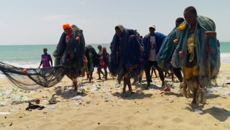Afrikanische-Menschen-Tragen-Fischernetze-An-Einem-Strand-Von-Moree,-Cape-Coast,-Ghana