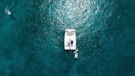 Top-Down-Drohnenaufnahme-Einer-Segelyacht-Im-Türkisfarbenen-Wasser-Einer-Tropischen-Insel
