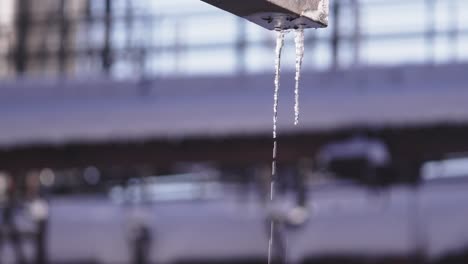 Close-up-of-melting-icicles-hanging-from-a-metal-pipe