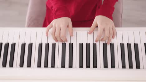 Close-up-of-black-white-piano-Keys-being-played-by-Hands-of-Young-Child-wearing-Red-Clothes